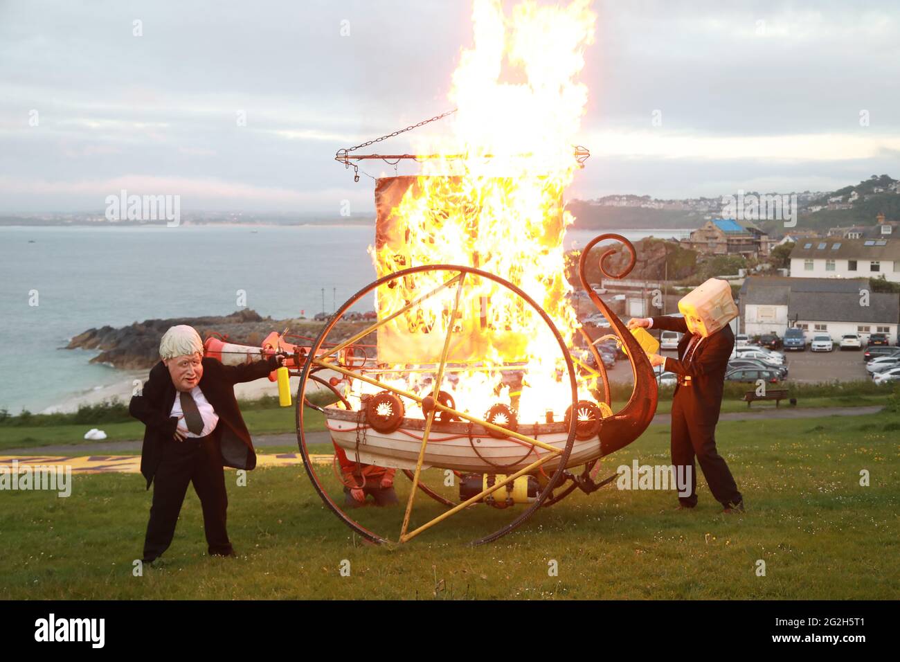 St Ives, Cornwall, UK. 11th June, 2021. Ocean Rebellion stage a fiery warning about the rising sea levels and the dangers of nit looking after oyr oceans. The message was aimed squarely at teh G7 leaders currently staying in Carbis Bay. Credit: Natasha Quarmby/Alamy Live News Stock Photo