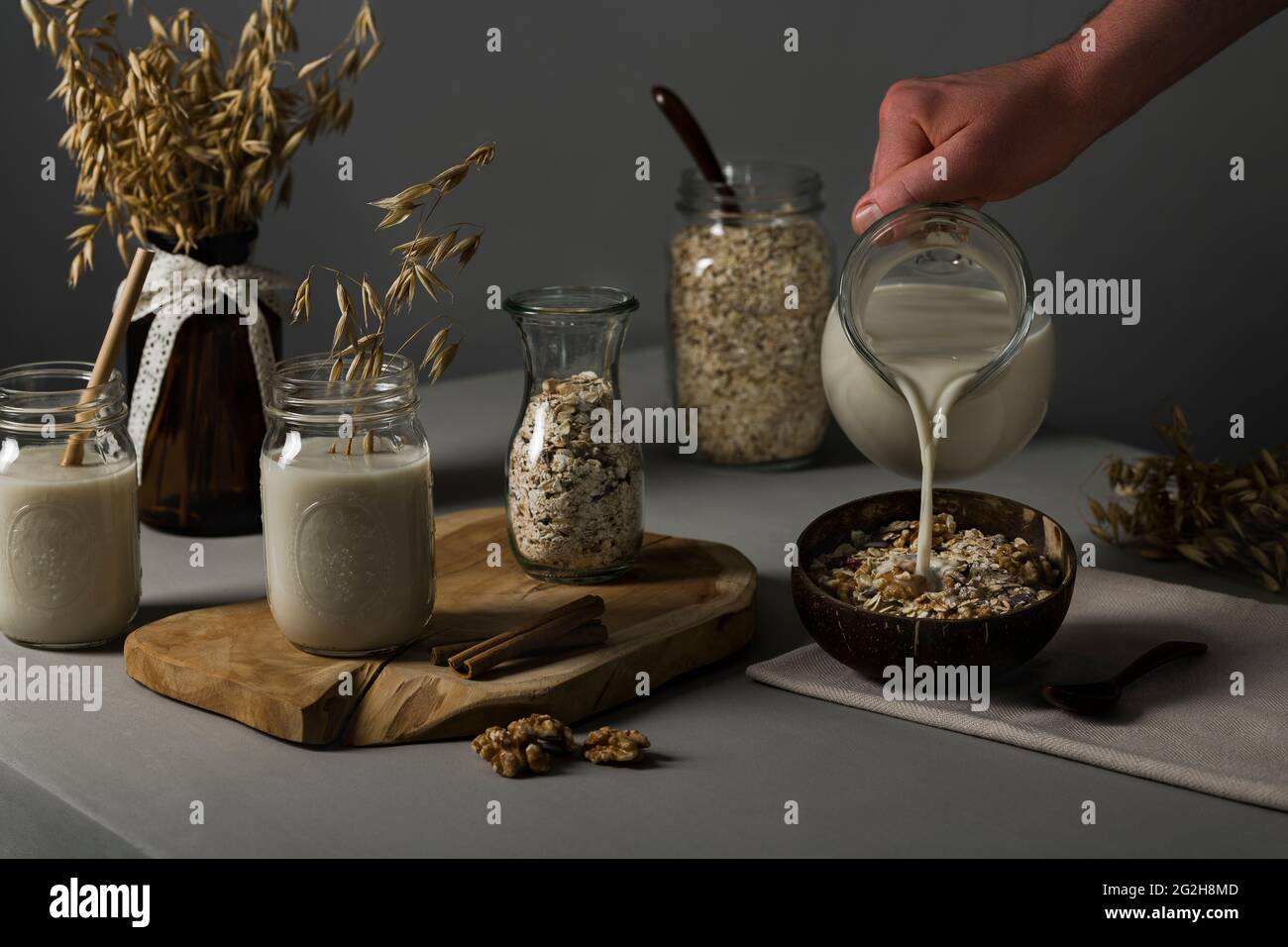 Oat milk, pour, muesli, walnuts, oat flakes, preserving jars, carafe, ears of wheat Stock Photo