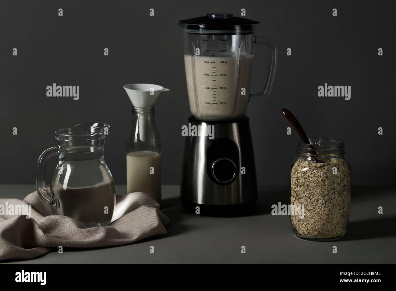 Oat milk, blender, mason jar, jug, milk bottle, funnel, kitchen towel Stock Photo
