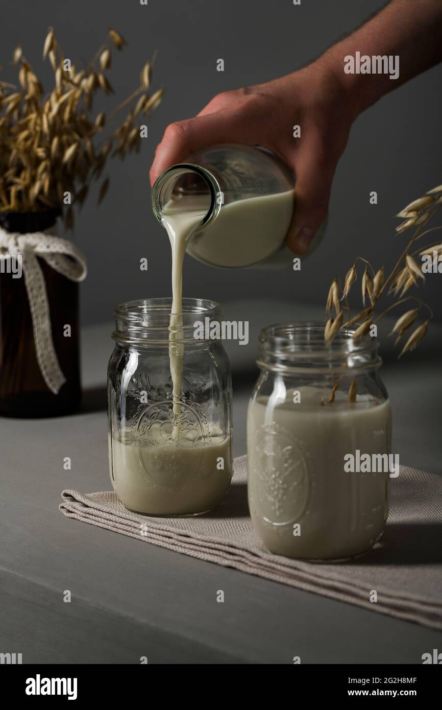 Oat milk, pour, mason jar, milk bottle, ears of wheat, kitchen towel Stock Photo