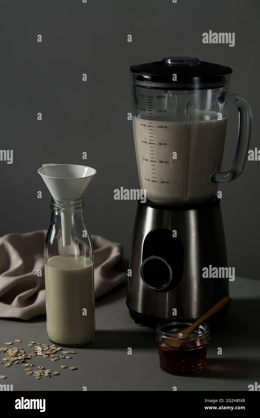Oat milk, blender, milk bottle, mason jar, maple syrup, kitchen towel Stock Photo