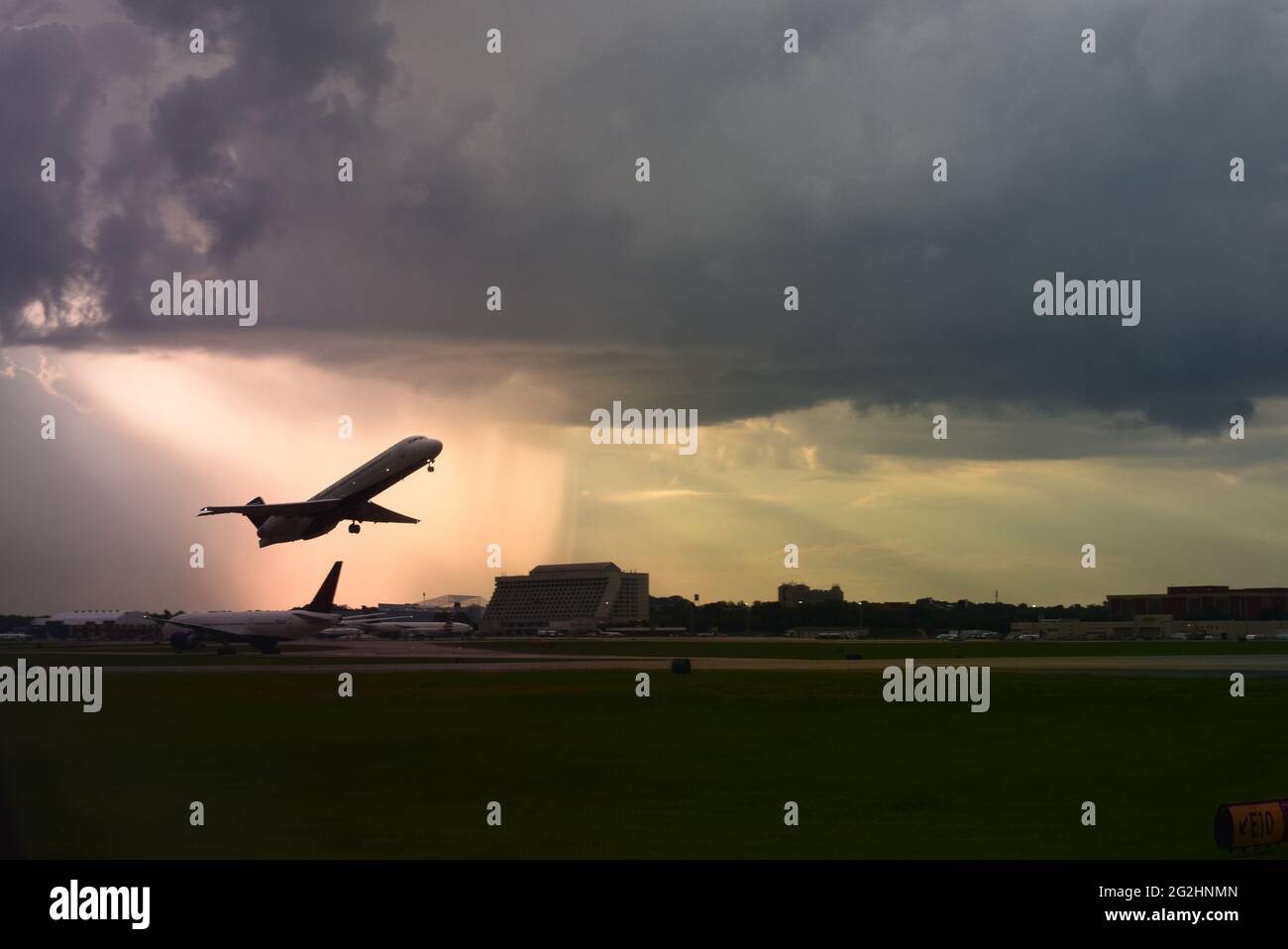 Small Regional Jet taking off from Hartsfield Jackson Atlanta Airport in Rain Storm during sunset Stock Photo