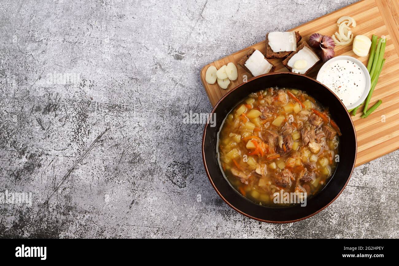 Shchi - traditional russian soup with beef and sauerkraut in a bowl on a dark background. Top view, flat lay Stock Photo