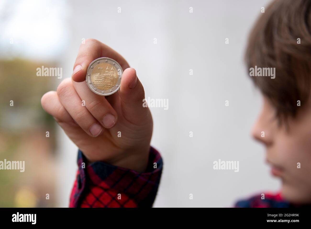 Germany, Saxony-Anhalt, Magdeburg, boy holds a 2 euro coin with Magdeburg Cathedral in his hand. Stock Photo