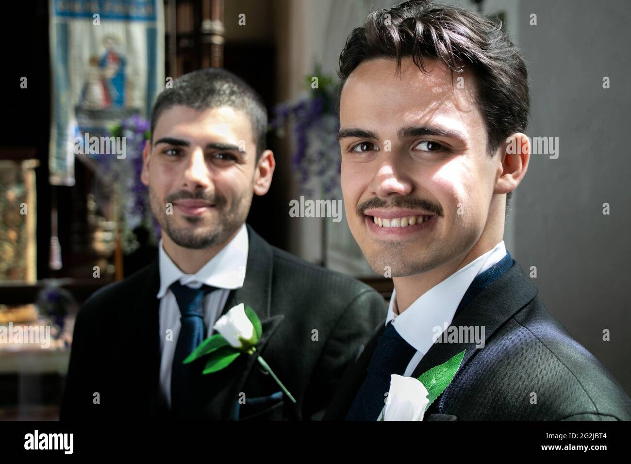 Smiling gay men sitting and waiting in church to be married. Stock Photo