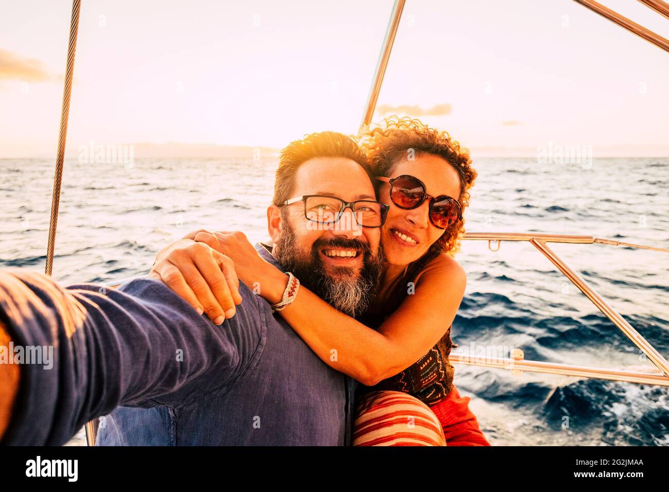 Cheerful and happy young adult couple smile and enjoy the sail boat yacht trip in summer day holiday vacation travel adventure lifestyle - love and romantic life Stock Photo