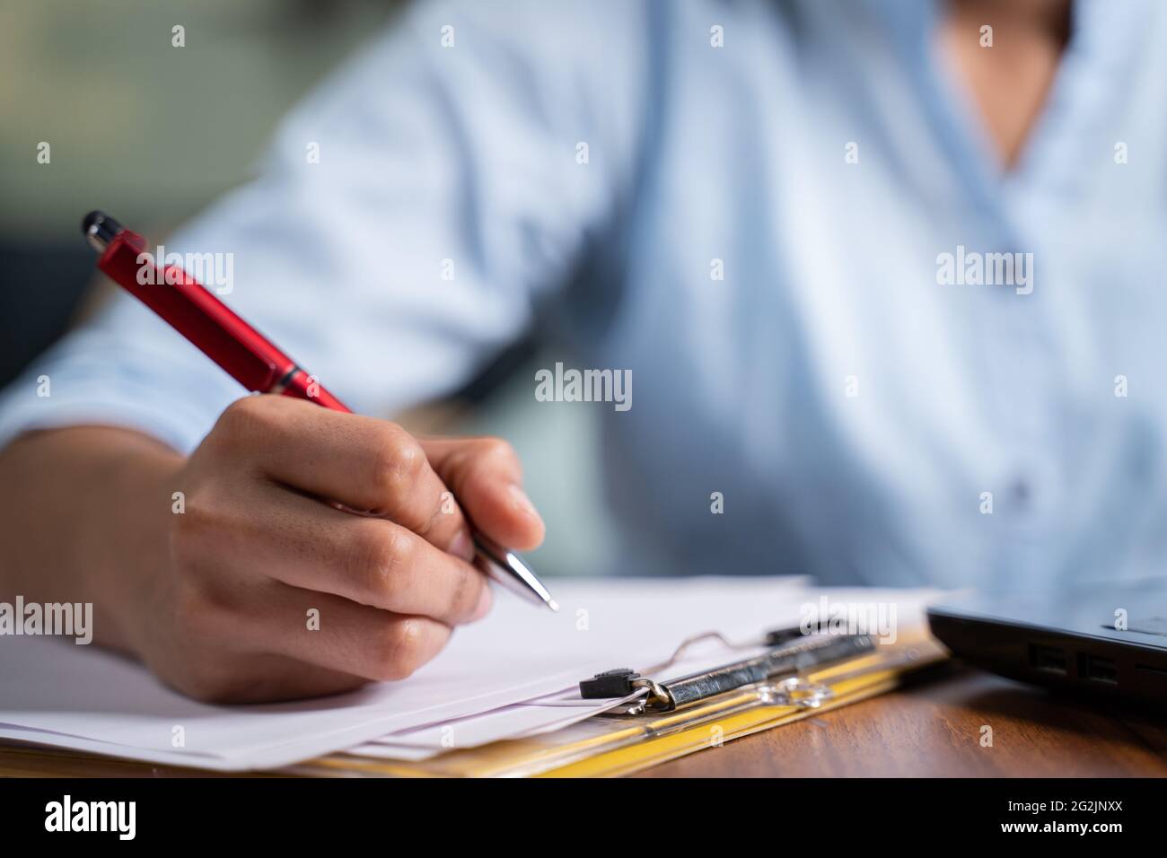 Focus on hand, Close up unrecognizable hands of Young business woman writing down notes at working desk - concept of employee or student online Stock Photo