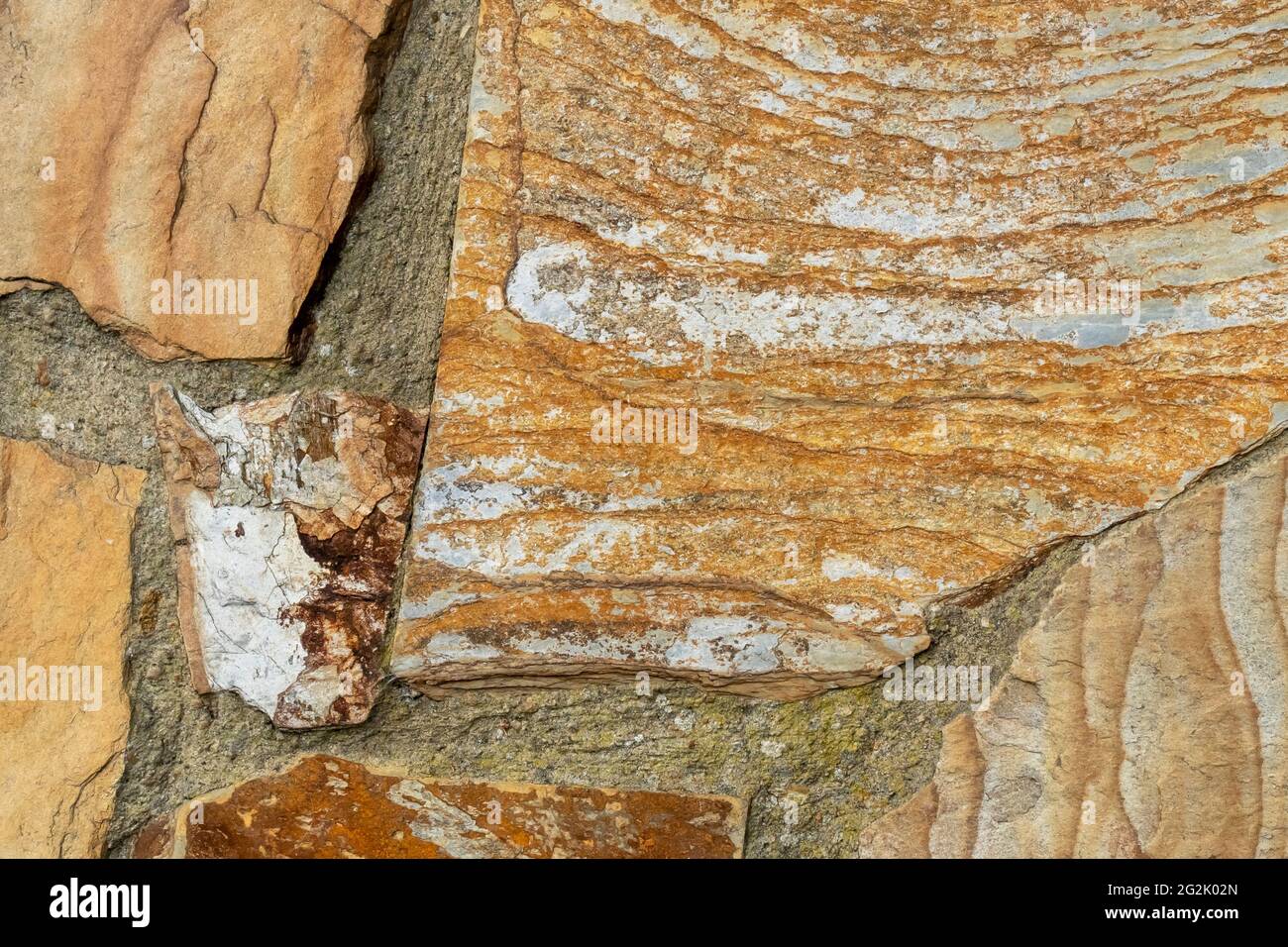 Stone wall with layered flaky peeling rocks close up. Natural abstract