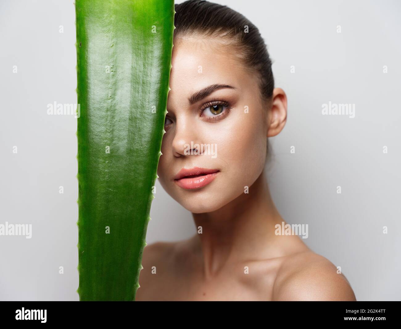 woman holding aloe leaf in front of her face and closed eyes clean skin ...