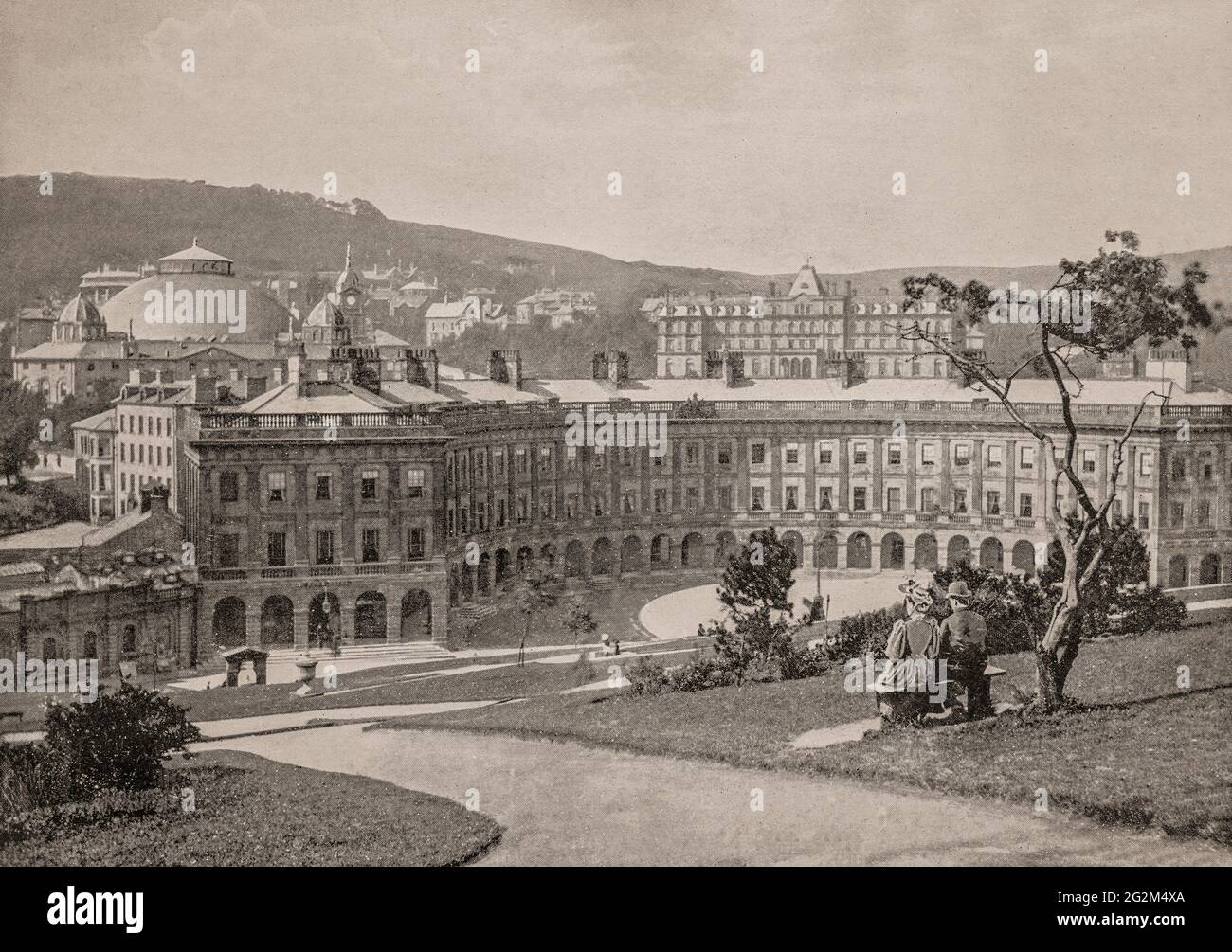 A late 19th century view of Buxton Crescent in the town of Buxton, Derbyshire, England from the Slopes, a steep landscaped hillside where warm spring water at a constant 27.5 °C (81.5 °F), has flowed for thousands of years from St Ann's Well. The crescent owing much to the Royal Crescent in Bath, was designed by the architect John Carr of York, and built for the 5th Duke of Devonshire between 1780 and 1789. Stock Photo