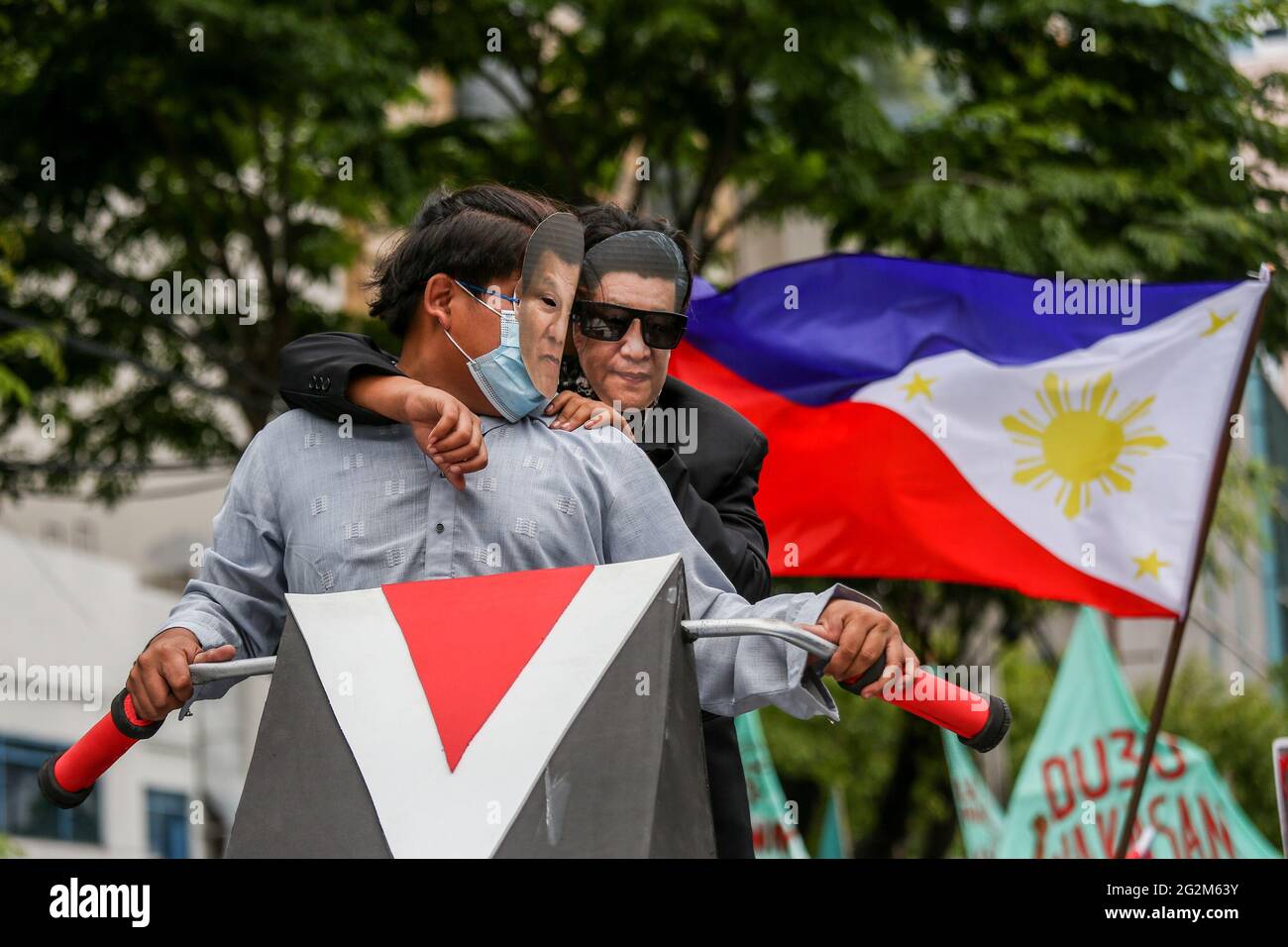 Metro Manila, Philippines. 12th June 2021. Activists wear a mask of Philippine President Rodrigo Duterte and Chinese President Xi Jinping during a protest to mark Independence Day in the financial district of Makati. Various groups called on China to stop its maritime activities in the disputed South China Sea, which endangers peace and stability in the region. Credit: Majority World CIC/Alamy Live News Stock Photo