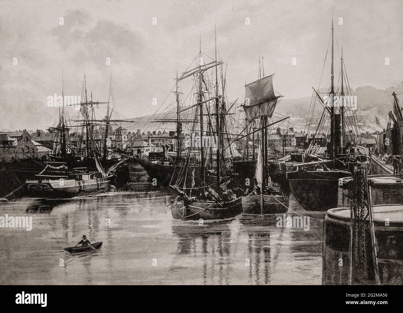 A late 19th century view of massed sailing ships in the harbour at Whitehaven, a town and port on the west coast of Cumbria, historically in Cumberland, England. With a growing export of coal through the harbour from the 17th century onwards it also became a major port for trading with the American colonies, and was, after London, the second busiest port of England by tonnage from 1750 to 1772. However, the port's trade waned rapidly when ports with much larger shipping capacity, such as Bristol and Liverpool, began to take over its main trade. Stock Photo