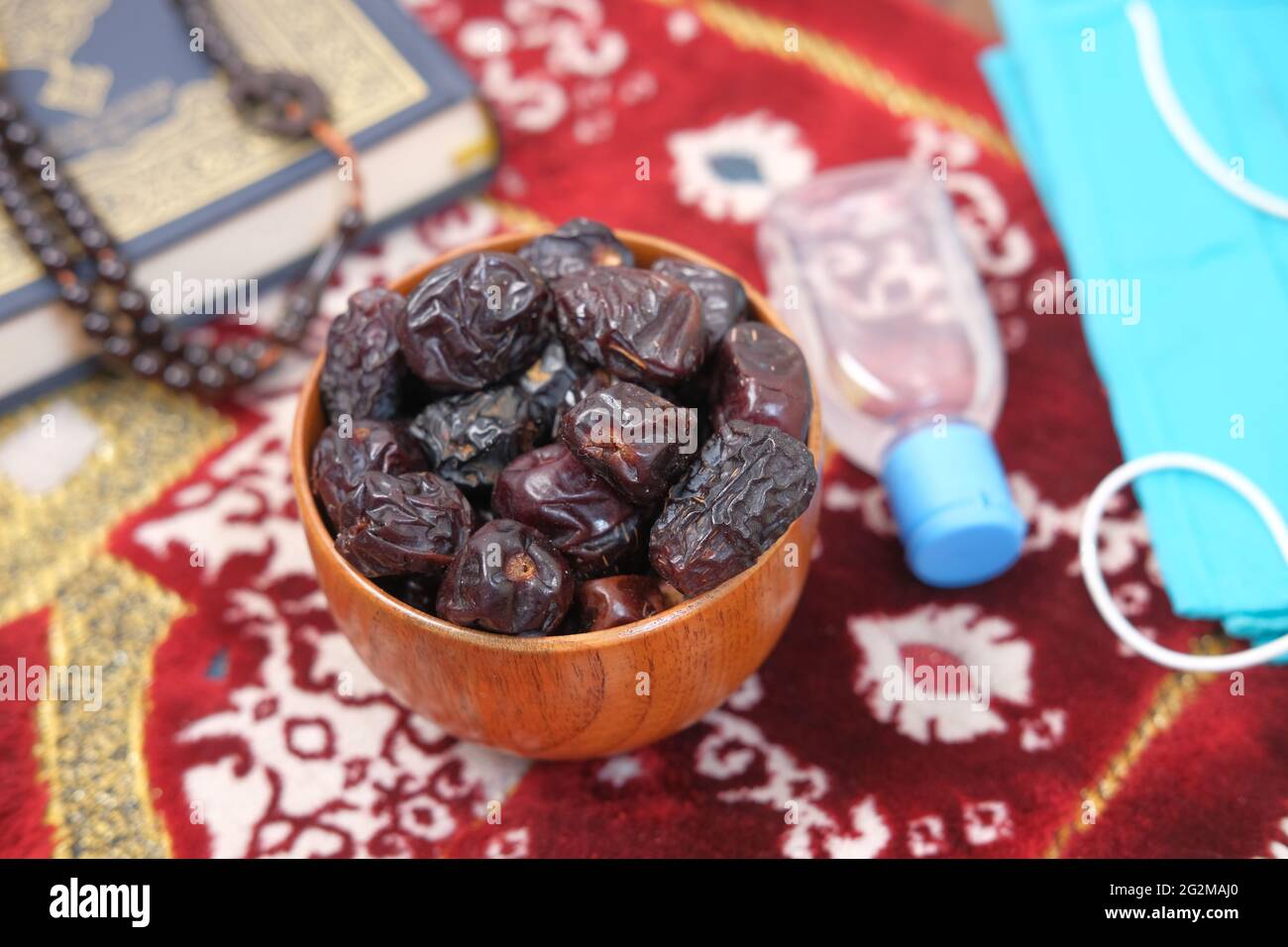 fresh date fruit in a bowl , prayer rosary , hand sanitizer and mask on floor  Stock Photo