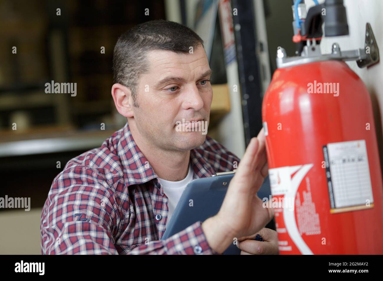 male technician checking fire extinguisher writing on document Stock Photo Alamy