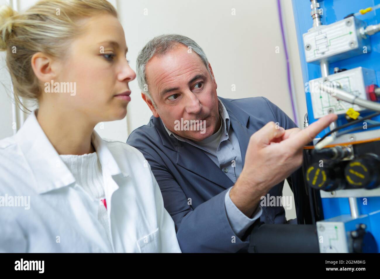 engineer instructing female apprentice on use of cnc machine Stock Photo