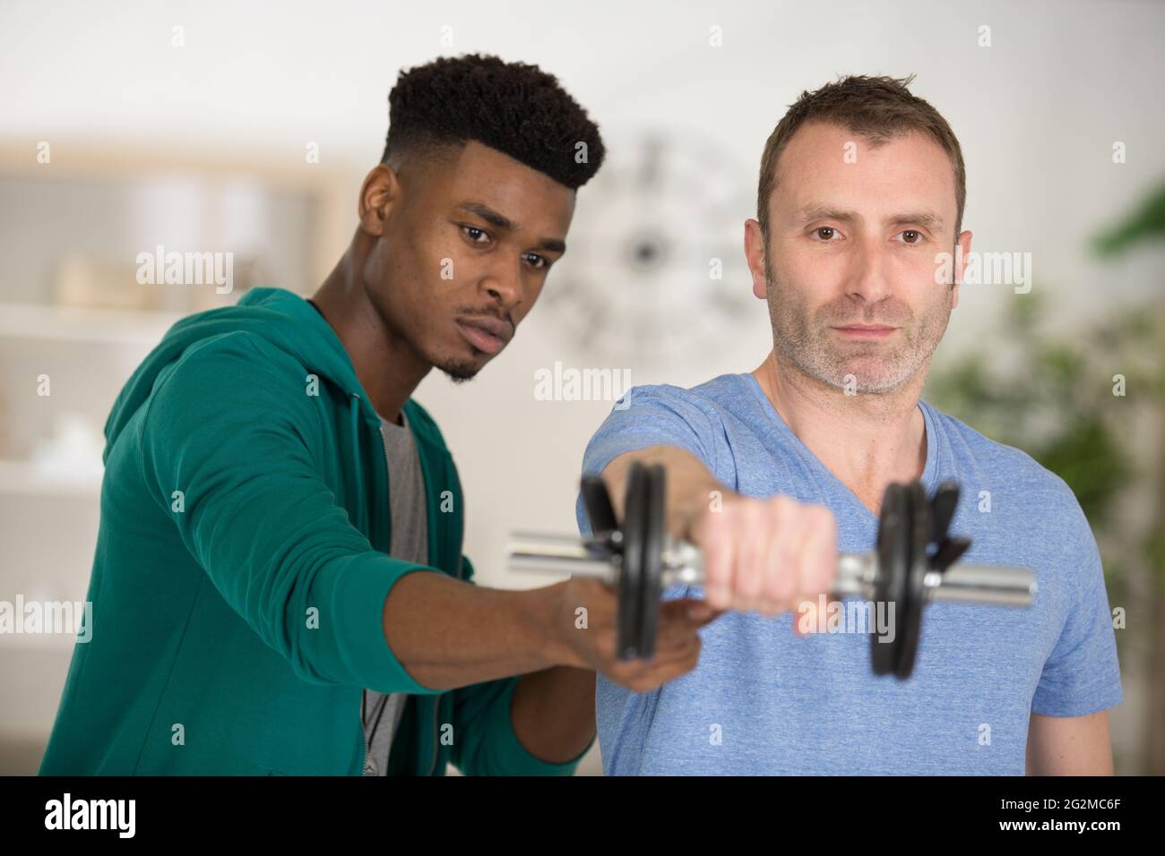 man raising hands while exercising with barbells Stock Photo Alamy