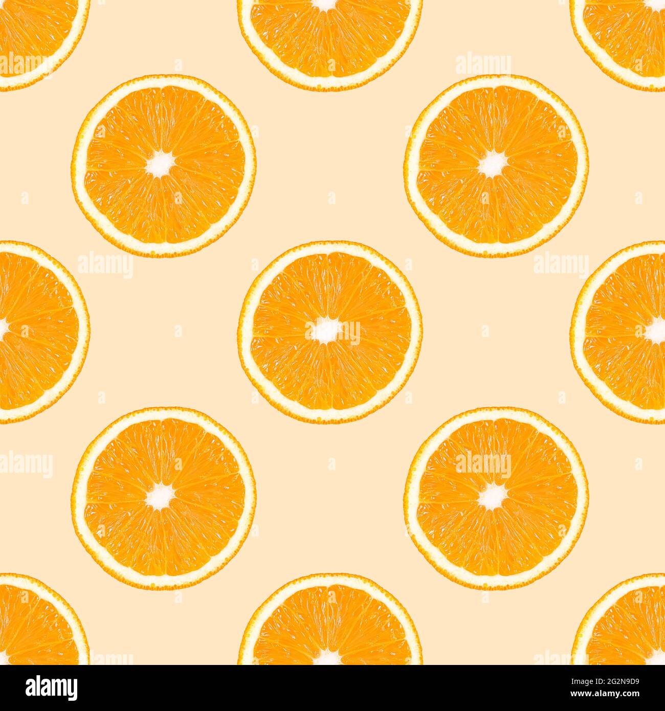 Seamless pattern made from orange fruit slices on a beige background. Stock Photo