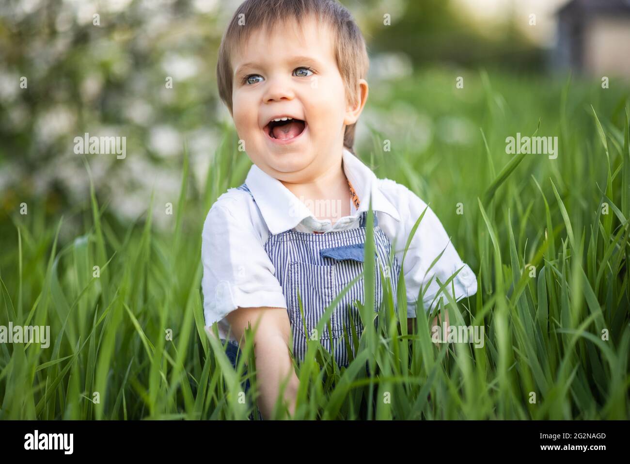 A little boy in denim overalls with expressive blue eyes. Jumping and