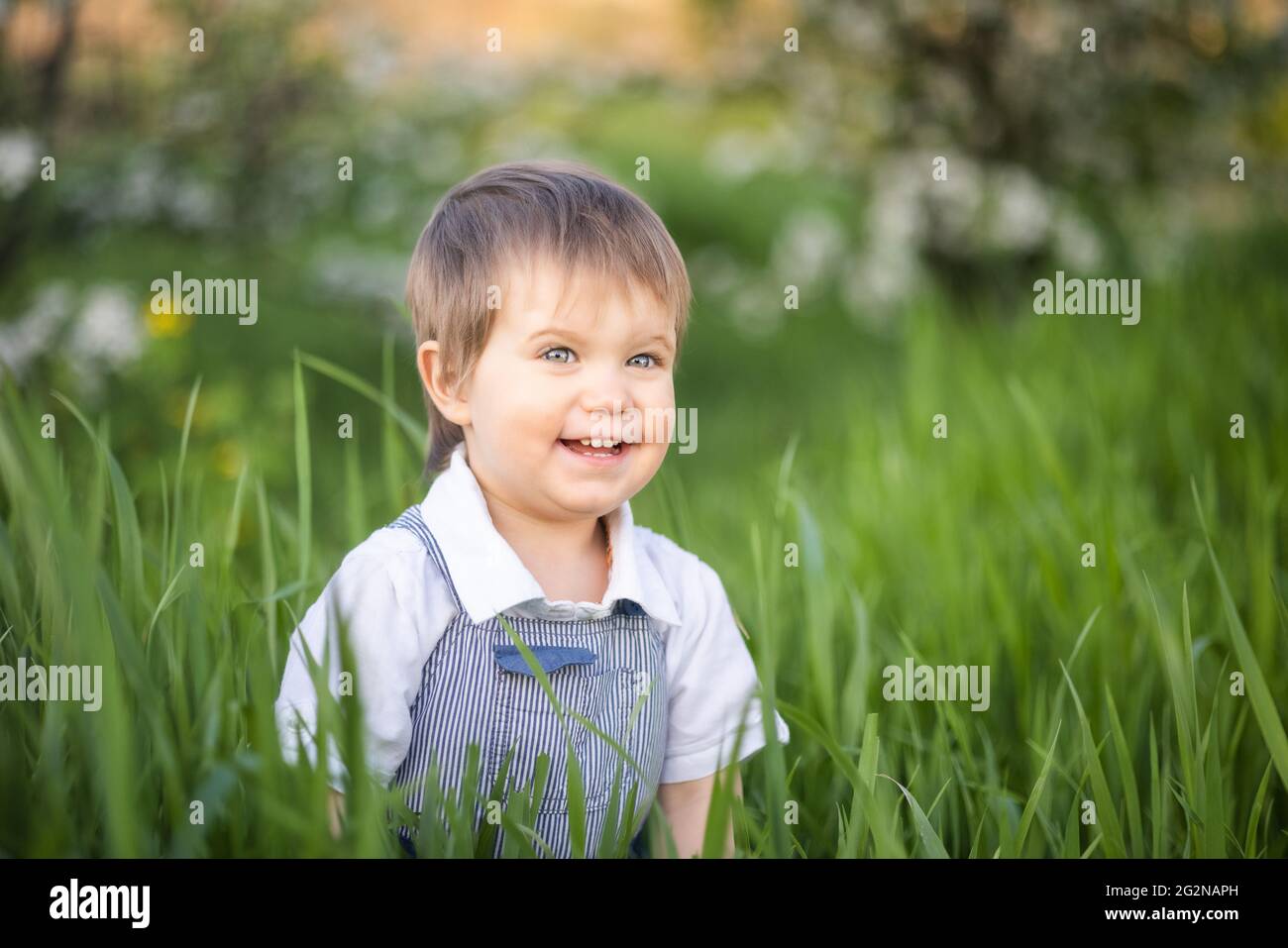A little boy in denim overalls with expressive blue eyes. Jumping and
