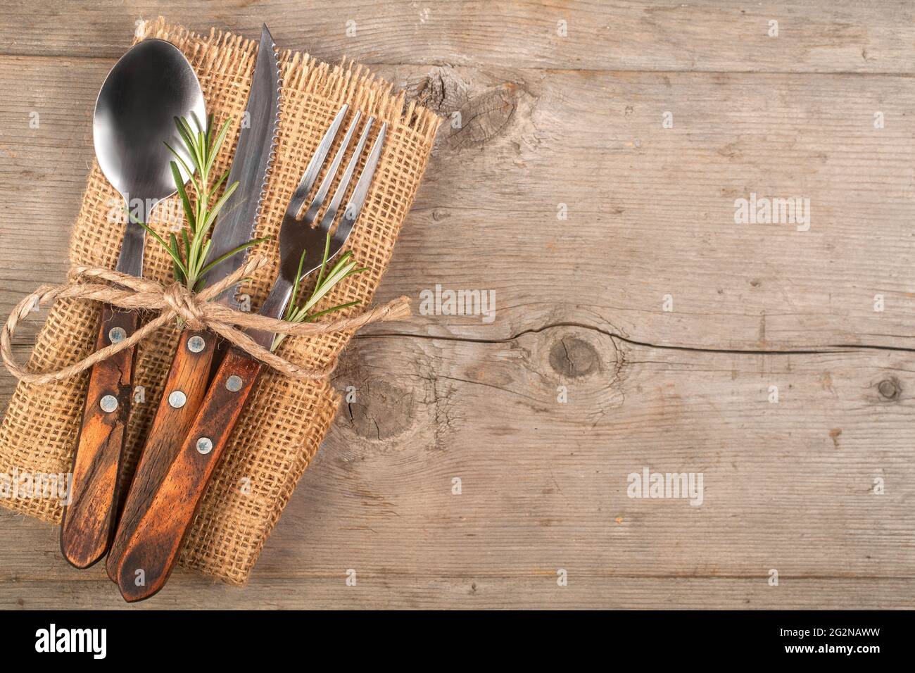 Spoon, fork, and knife along with linen napkin on the wooden background, retro style. Dining set. Restaurant cutlery. Stock Photo