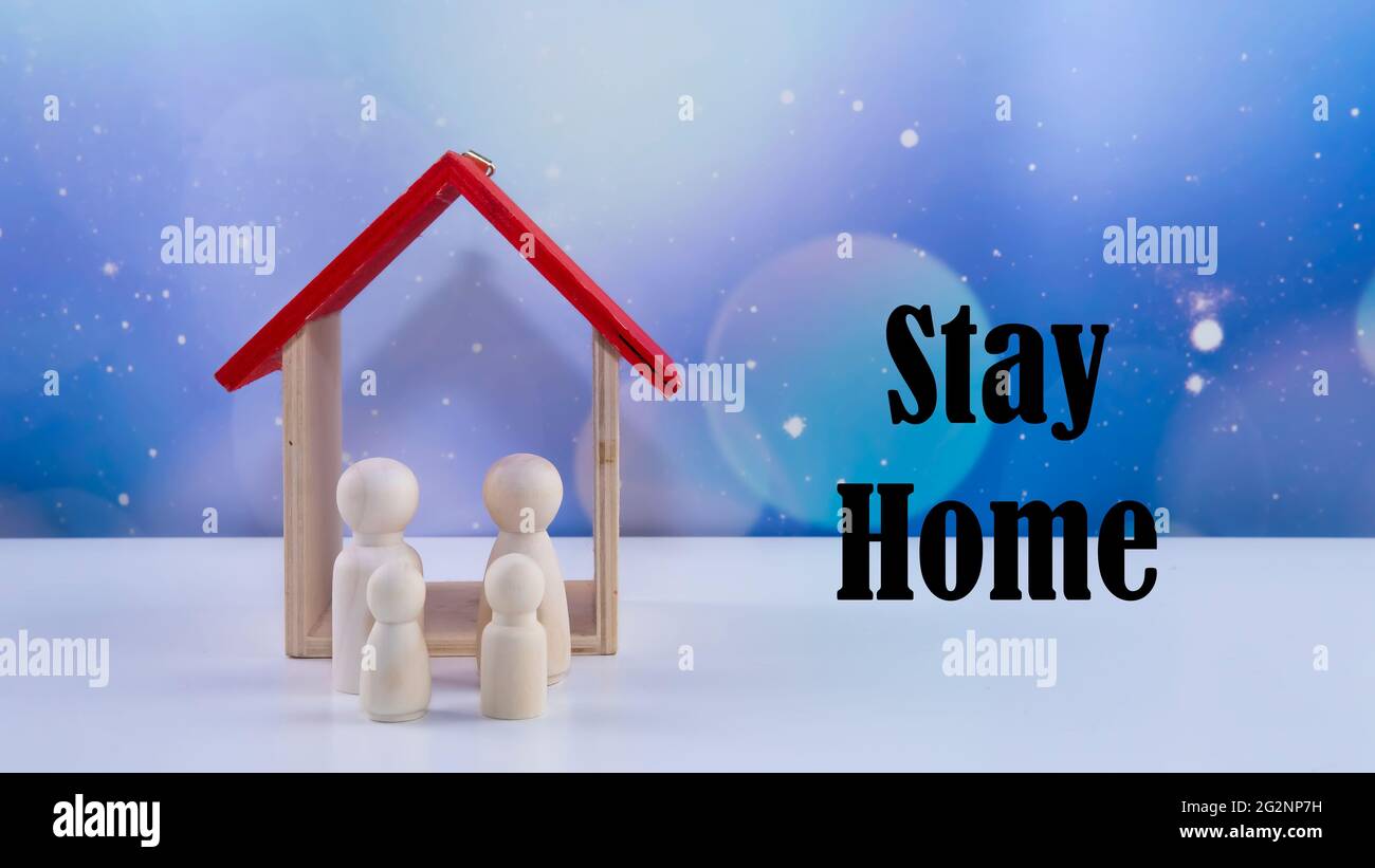 Words stay home,  concept of self quarantine at home as preventative measure against virus outbreak. Selective focus of a wood people and a house with Stock Photo