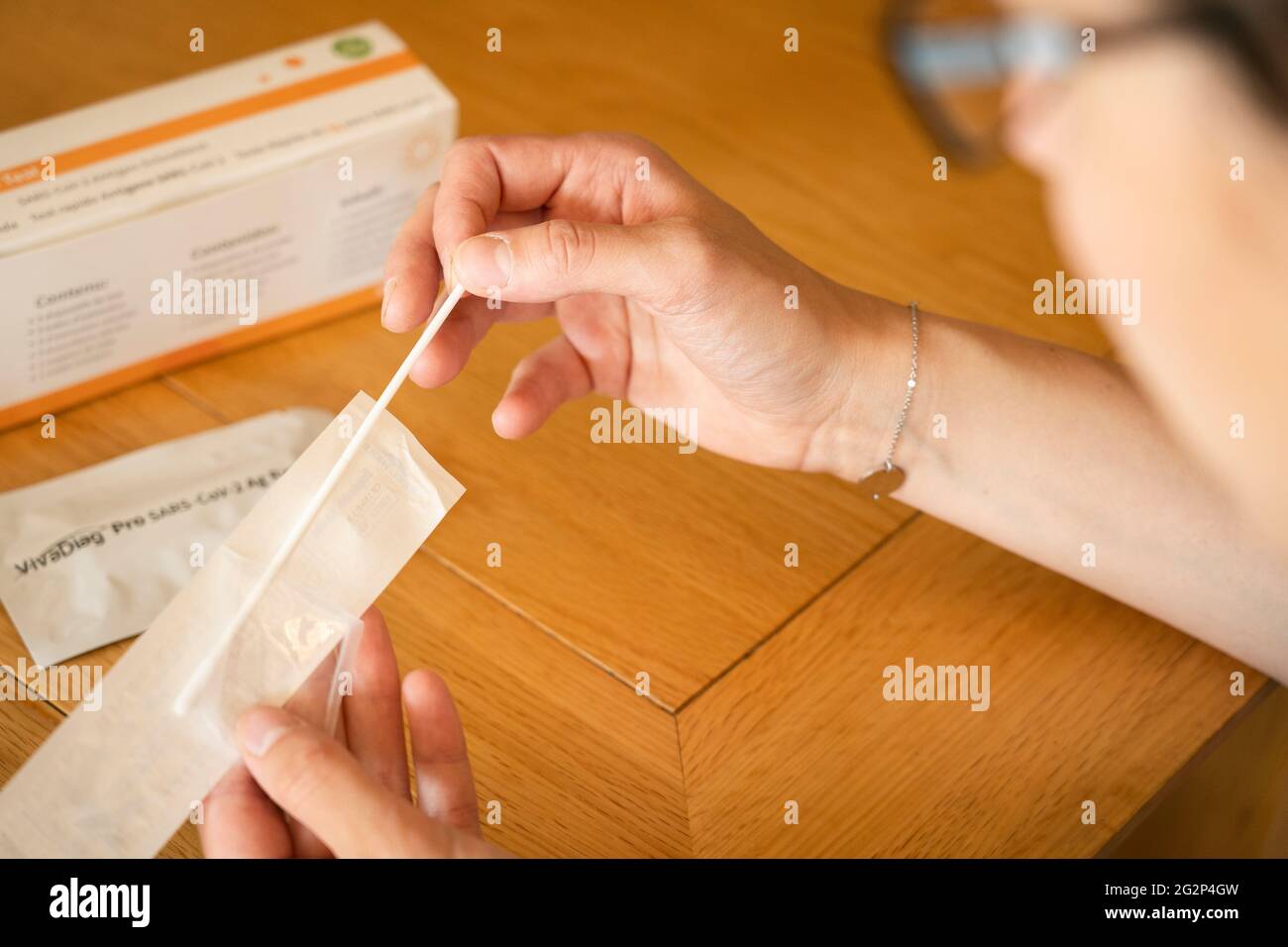 A woman pulling out a nasal swab for taking a self diagnostic VivaDiag SARS-CoV-2 Ag Rapid Test for Covid-19 at home Stock Photo