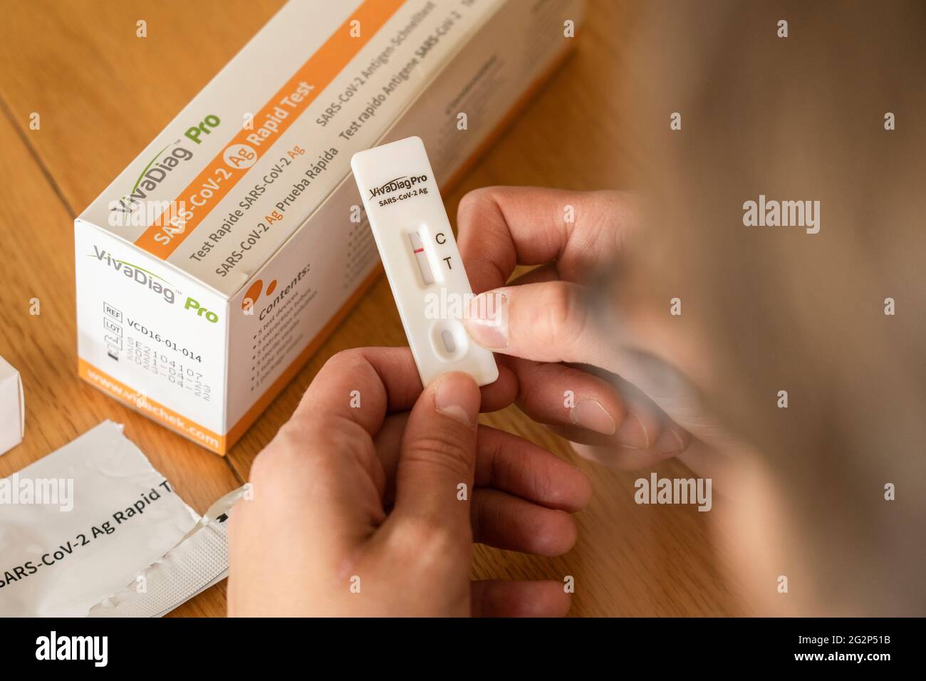 A woman looking at a negative test result after taking a self diagnostic VivaDiag SARS-CoV-2 Ag Rapid Test for Covid-19 at home Stock Photo