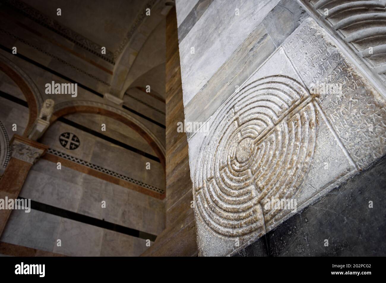 Cathedral of Lucca (Tuscany, Italy). Detail of the ancient famous maze column on the facade, decorated with a medieval labyrinth over the white marble Stock Photo