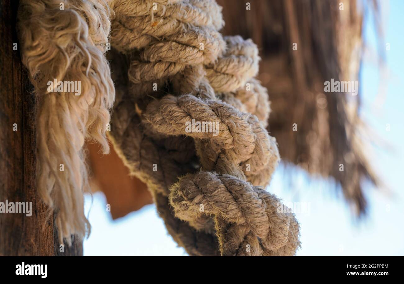 Thick natural fiber rope knot tied at beach hut, closeup detail Stock Photo