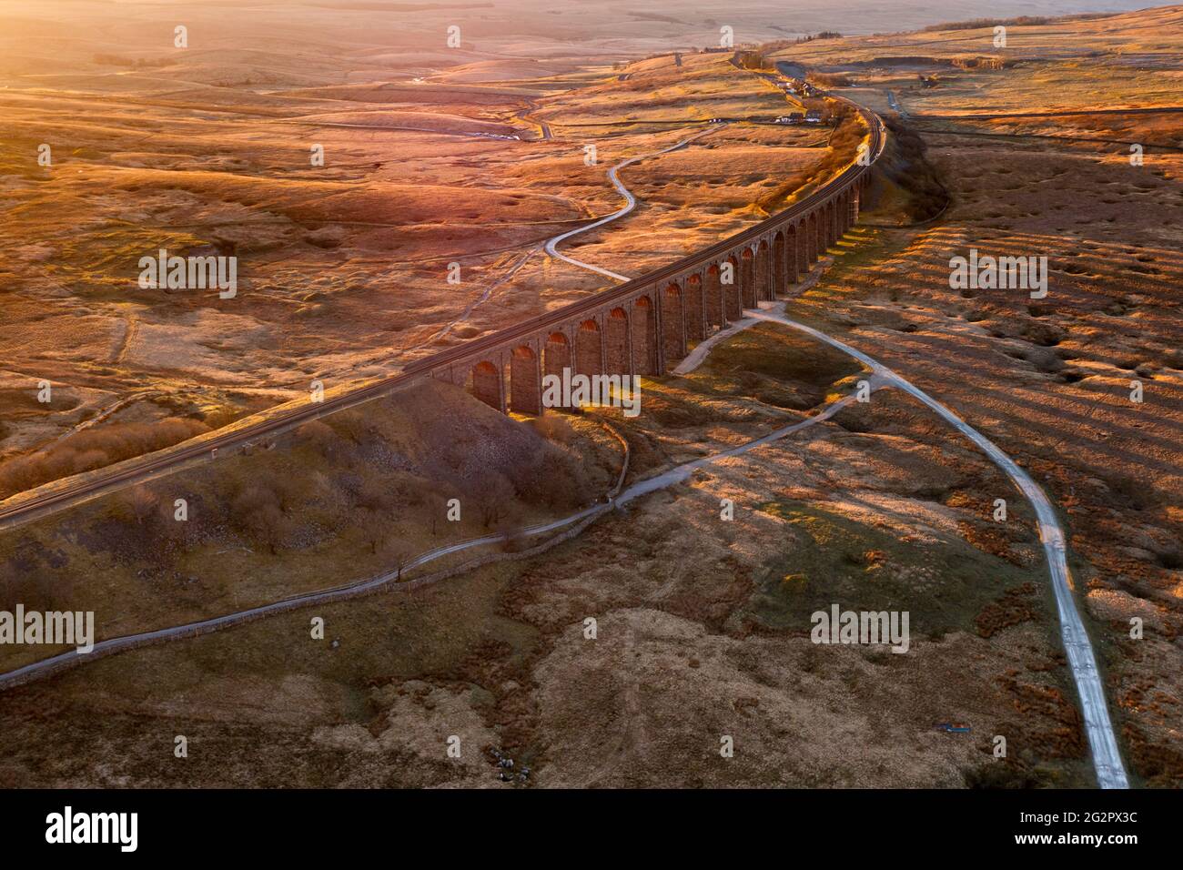 Beautiful golden light from the morning sun at Ribblehead Viaduct in the Yorkshire Dales, UK. Aerial drone photography. Stock Photo