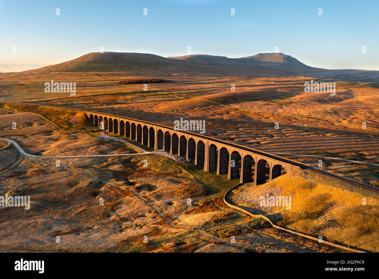 Golden morning light on Ribblehead Viaduct arches surrounded by wide open moorland. Taken with a drone in the Yorkshire Dales National Park, UK. Stock Photo