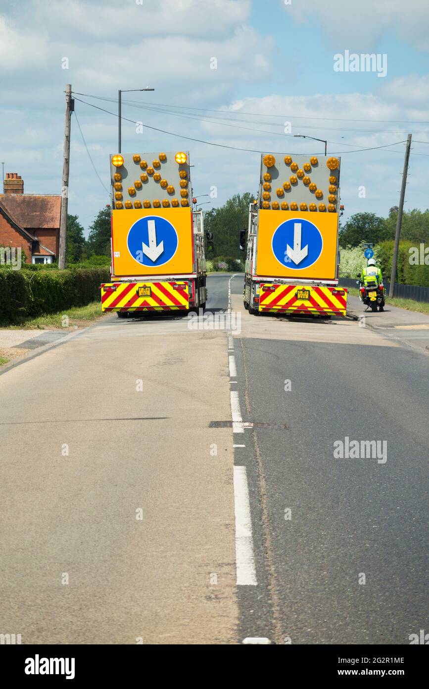 Police mobile / moving rolling road block rd closure enforced by 2 HGV highway maintenance lorry heavy goods vehicle parked in the road / lane. Windsor UK (123) Stock Photo