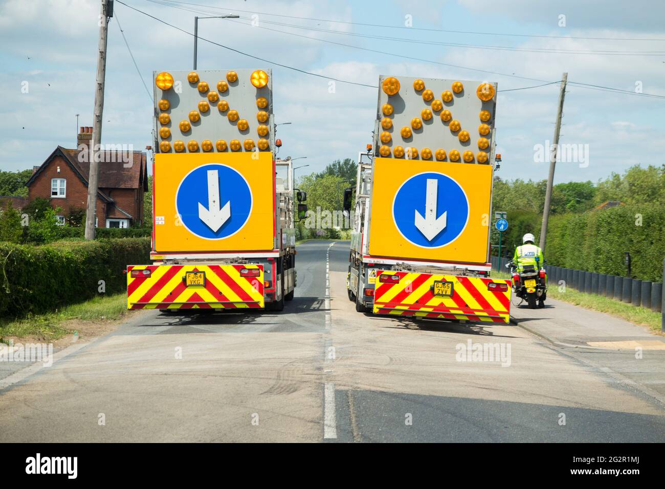Police mobile / moving rolling road block rd closure enforced by 2 HGV highway maintenance lorry heavy goods vehicle parked in the road / lane. Windsor UK (123) Stock Photo
