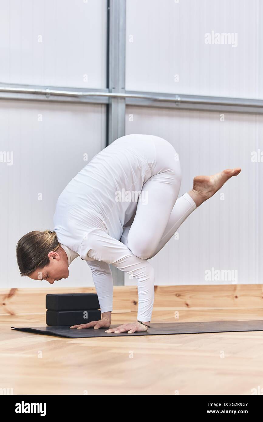 complicated inverted yoga asana. Crane posture Bakasana in Latin Caucasian woman. Stock Photo