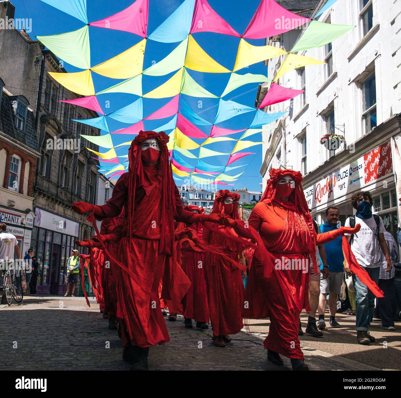 Falmouth, Cornwall, UK 12th June 2021 Extinction rebellion march in protest at business and government ‘greenwashing’ polices at the G7 summit. The red rebels lead the march through the town centre joining with the doctors of XR and dirty scrubbers, finishing at the media centre. Stock Photo