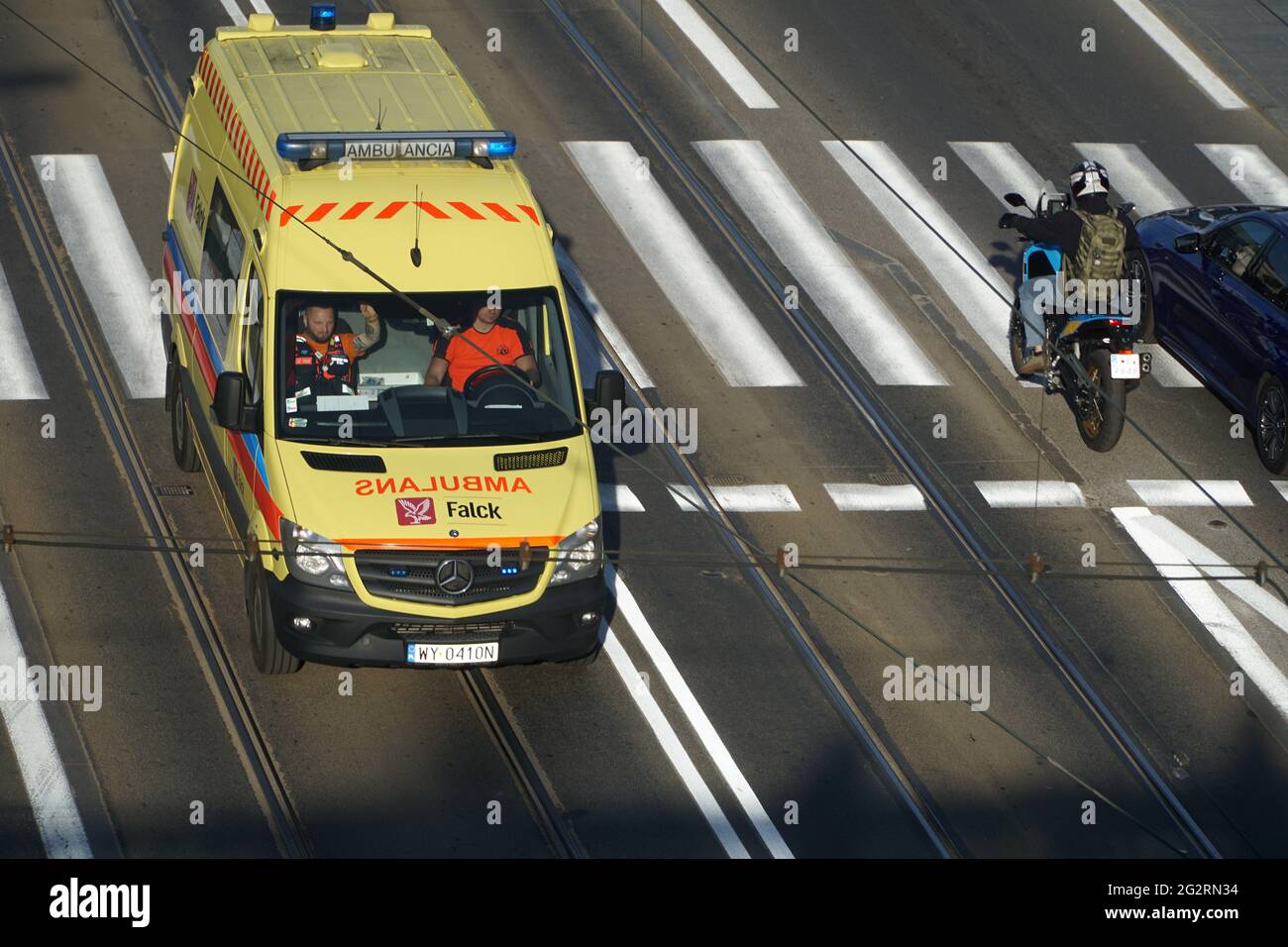 Warsaw, Poland - June 11, 2021: Yellow ambulance with flashing lights on rushing on tram track to bypass traffic jam on near the Warsaw Old Town. Stock Photo