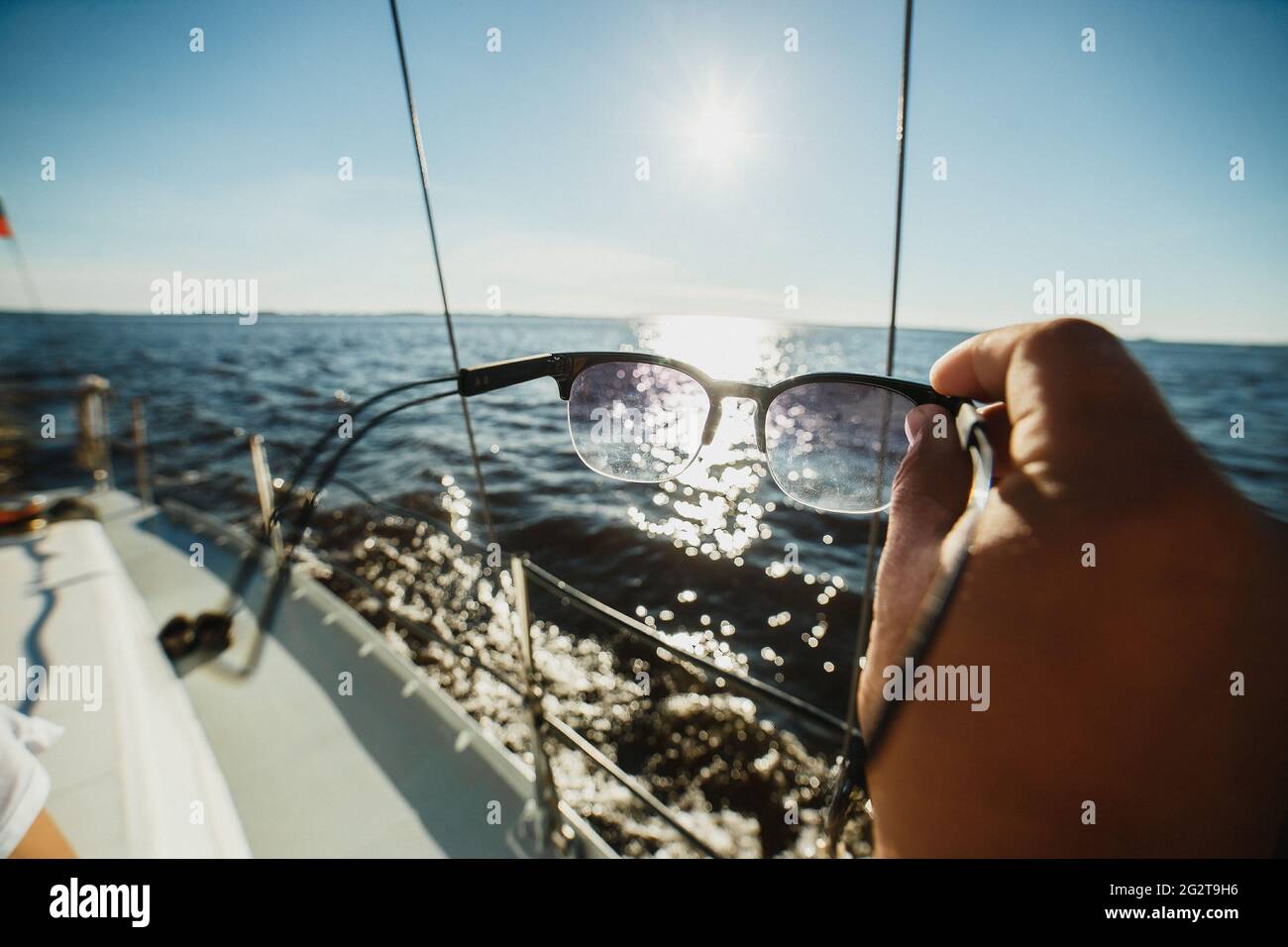 Sunglasses in hand against the sun and the sea on a yacht. Stock Photo