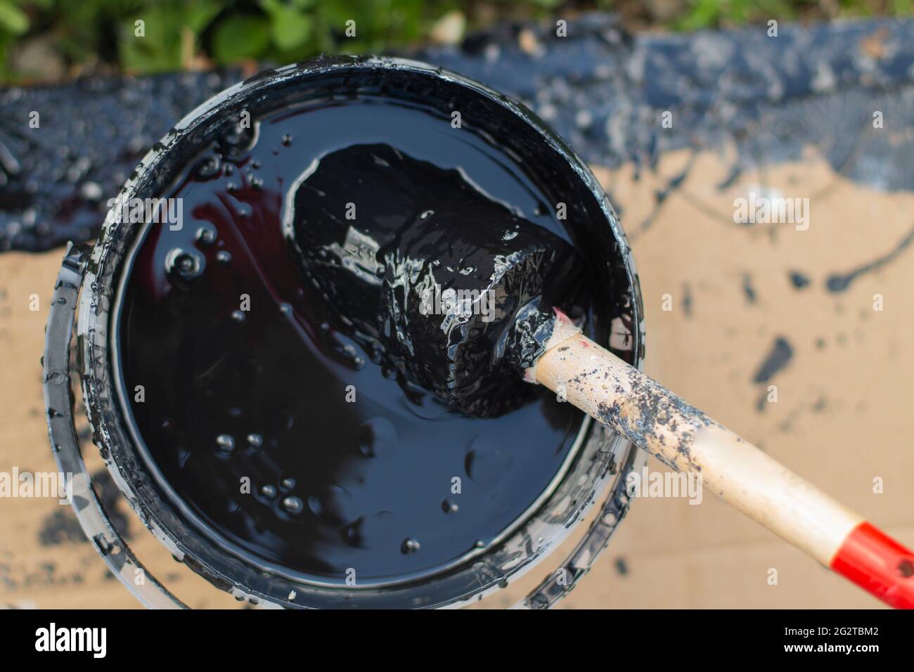 Paint brush in a bucket. Black paint for wood. Brush in a thick layer