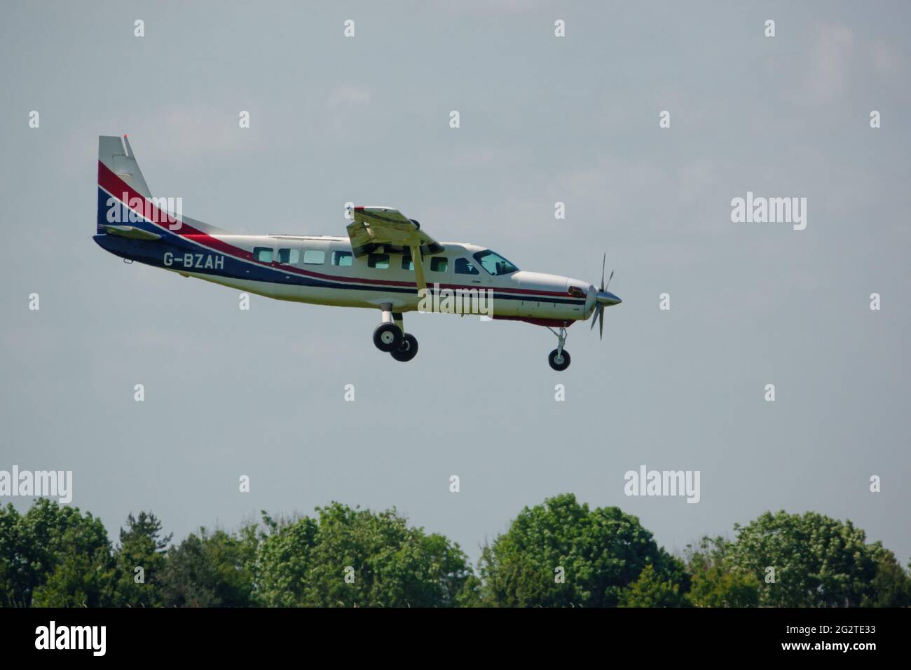 a cessna grand caravan 208B aircraft returns to land on a grass runway having dropped the Red Devils parachute display team Stock Photo