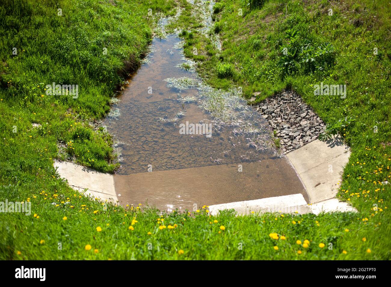 Water drain. Slope to drain water from the road. Hydrocommunications along the highway. Concrete drain. Ditch for protection from rain. Stock Photo