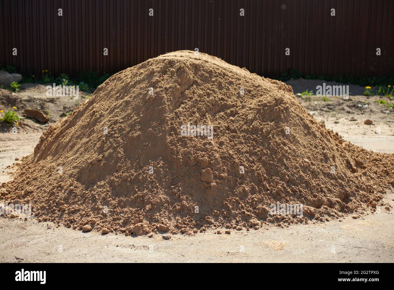 A mountain of sand. Building material on the street. Fine sand for the road. The sand is piled up in one heap. Stock Photo