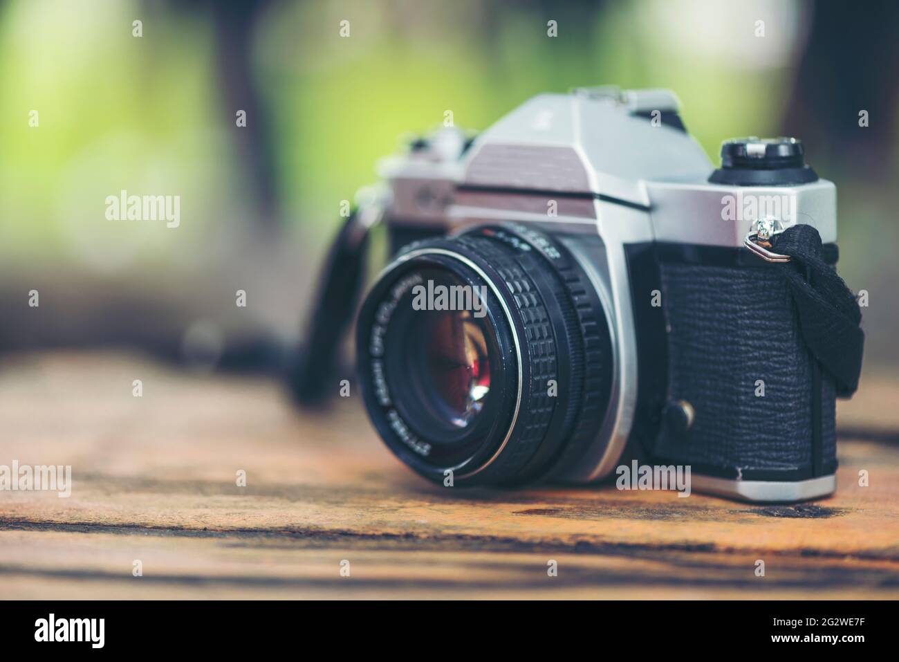 35mm SLR camera for classic photography old retro style. Black camera wide lens on wooden table outdoor. Vintage camera equipment. Stock Photo