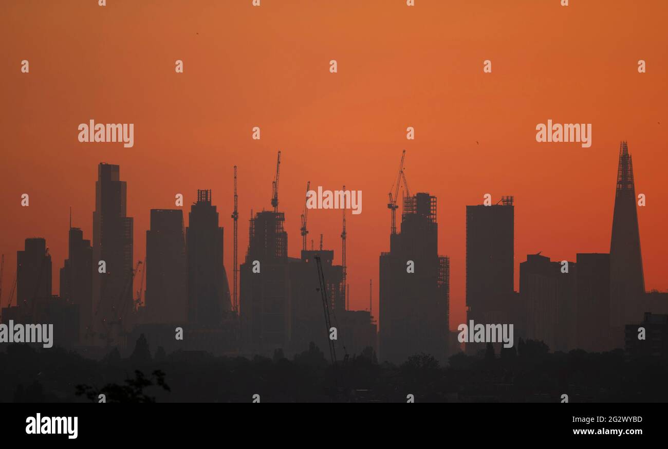 Wimbledon, London, UK. 13 June 2021. Orange and cloudless dawn sky behind London skyscrapers begins a day of heat in London with temperatures due to reach 27 degrees by afternoon. Credit: Malcolm Park/Alamy Live News. Stock Photo