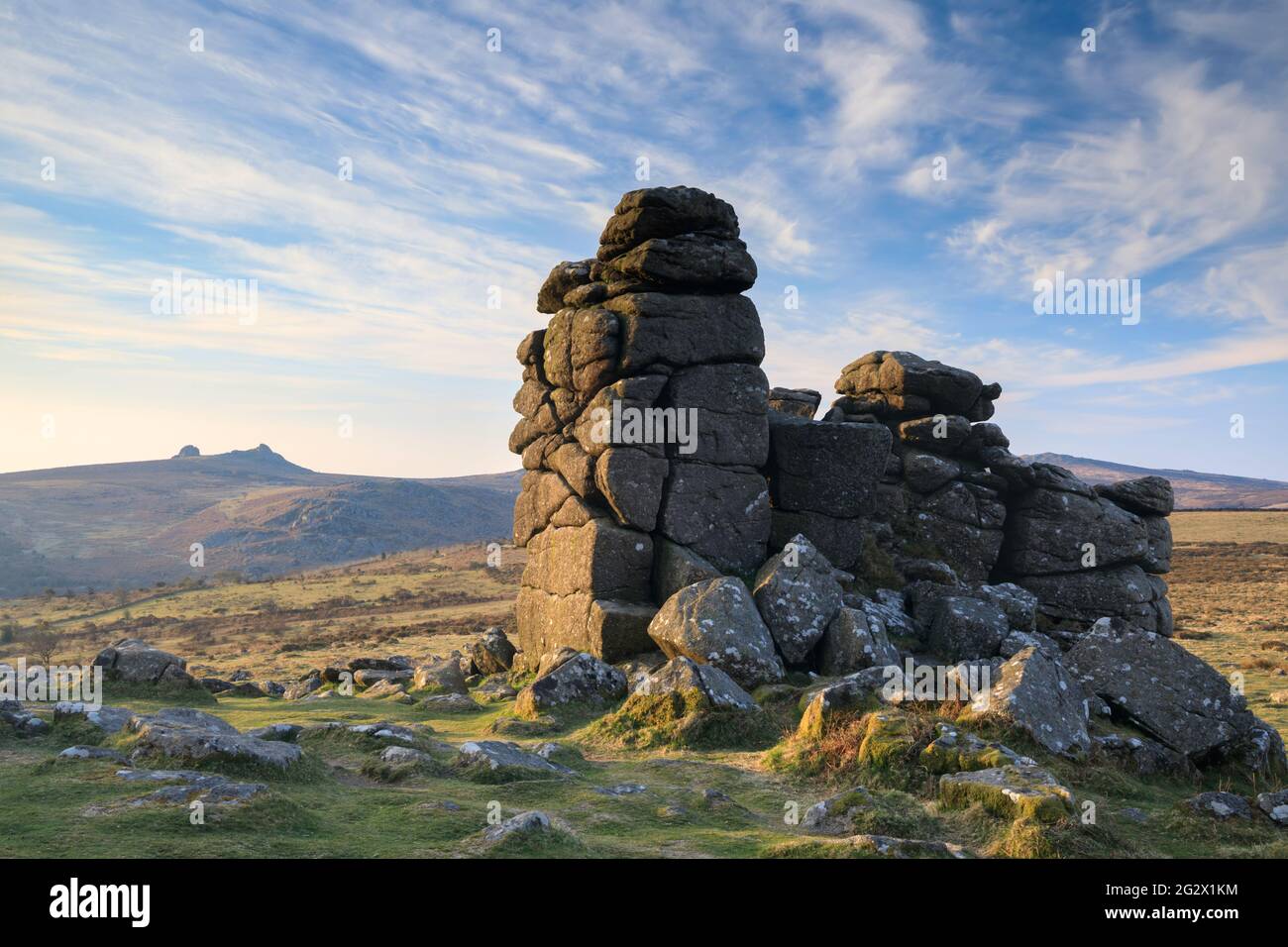 The photograph features rocks on Hound Tor in the Dartmoor National Park in Devon captured shortly after sunrise with Haytor in the distance. Stock Photo