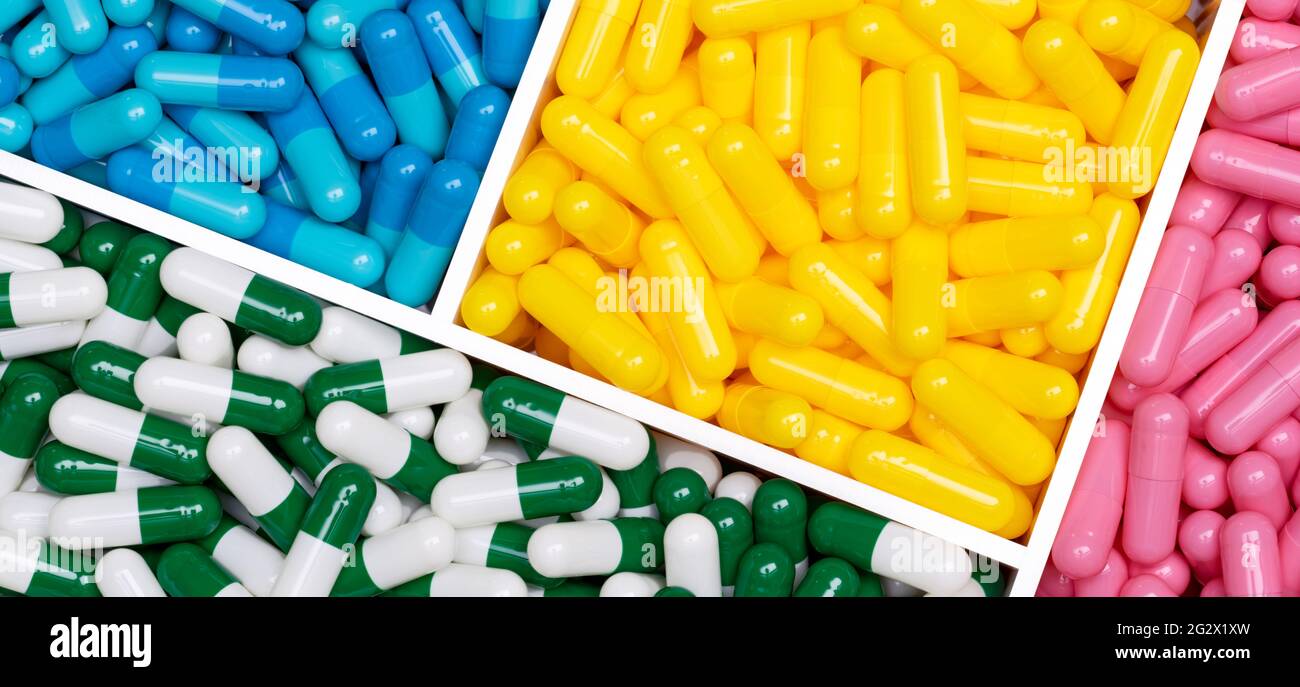 Top view of colorful capsule pills in plastic box. Pink, yellow, blue, green-white capsule pills in tray. Pharmacy web banner. Pharmaceutical industry Stock Photo