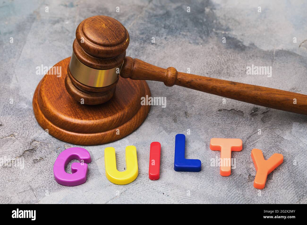 Judge gavel and word from multicolored plastic letters on table, guilt concept. Stock Photo
