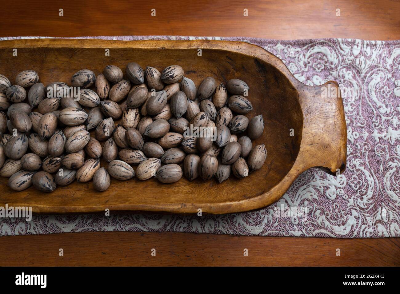 Raw in shell whole Pecan nuts in a wooden bowl on a wood table Stock Photo