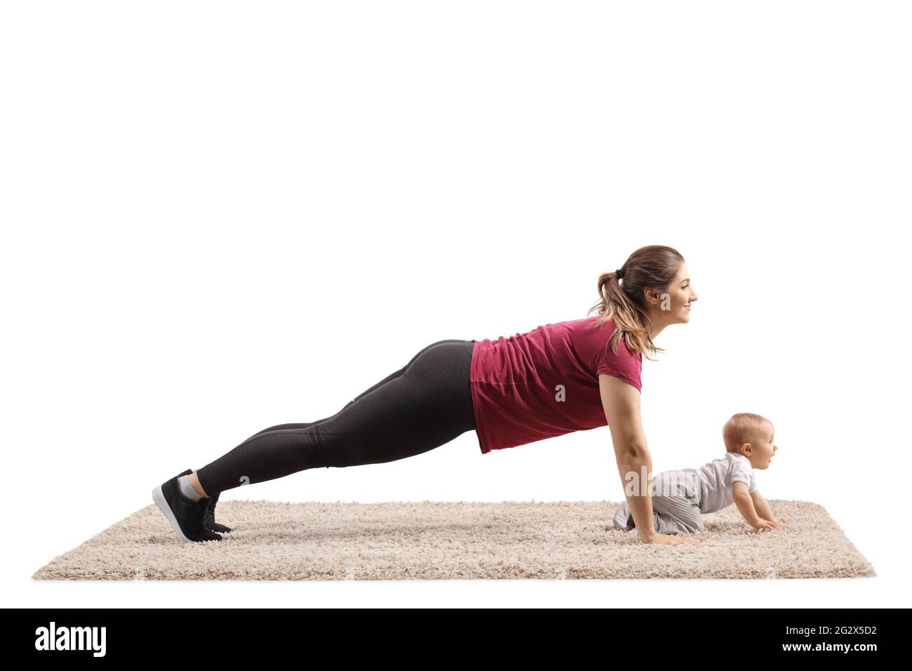 Young mother doing plank exercises with her baby crawling on carpet isolated on white background Stock Photo