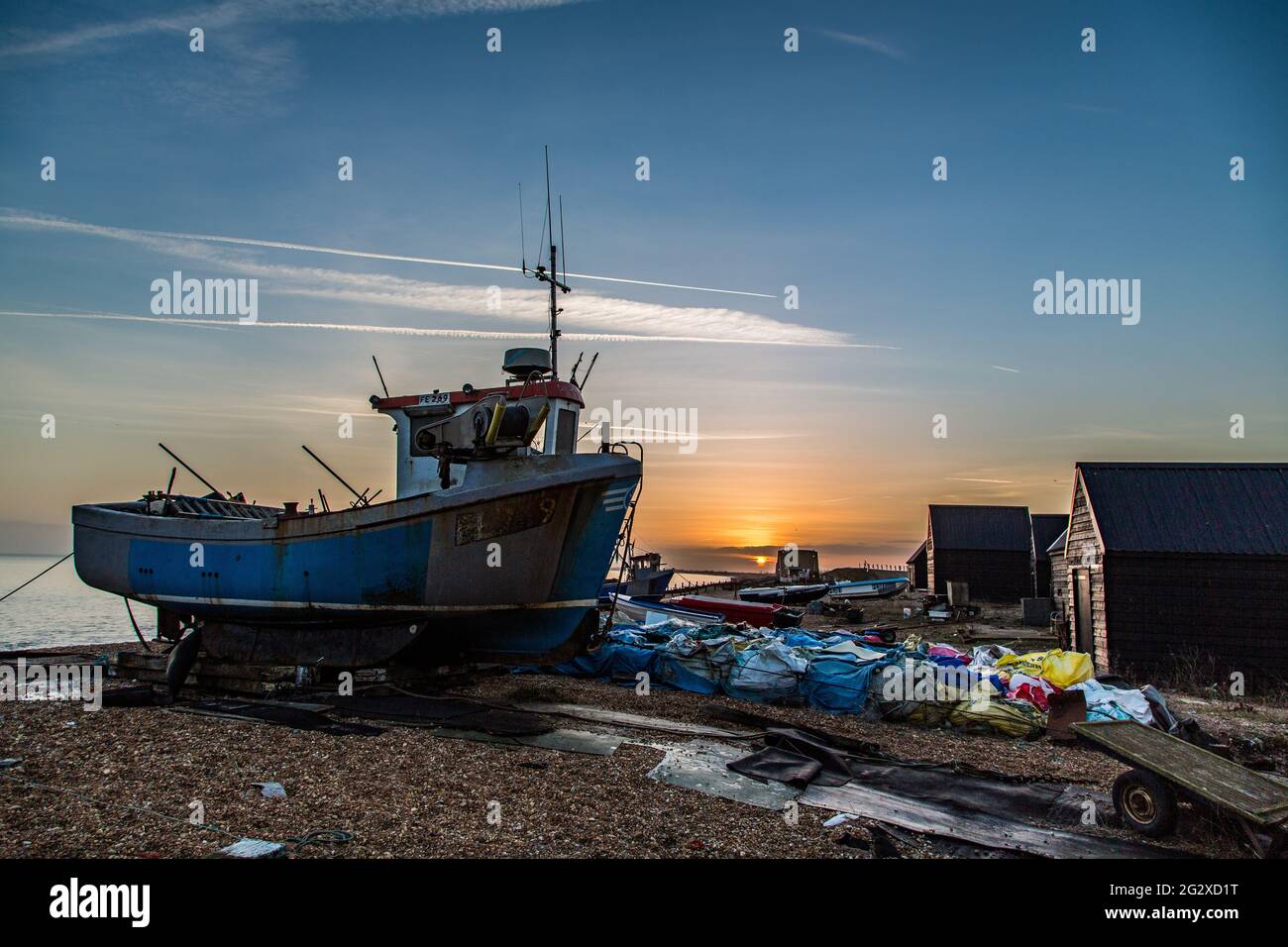 A fishing boat on the beach at sunset surrounded by equipment. Taken on