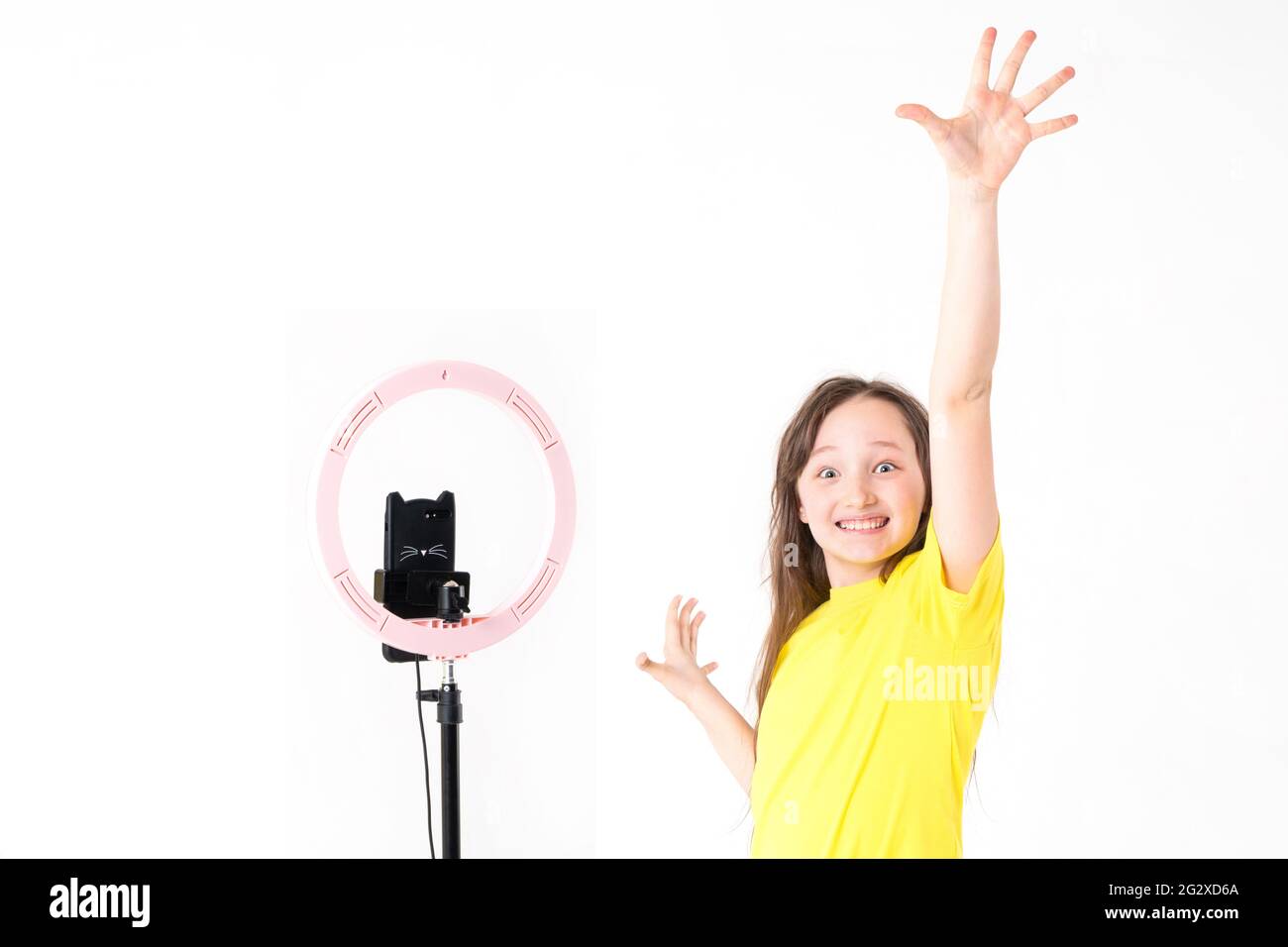 A teenage girl looks at the camera and raises her hand with an ...